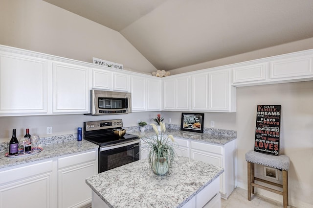 kitchen featuring white cabinets, light stone countertops, vaulted ceiling, and stainless steel appliances