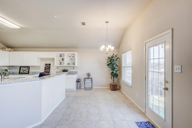 kitchen featuring white cabinets, lofted ceiling, light stone countertops, an inviting chandelier, and open shelves