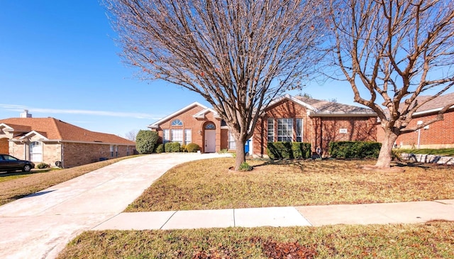 ranch-style home featuring concrete driveway, brick siding, and a front lawn