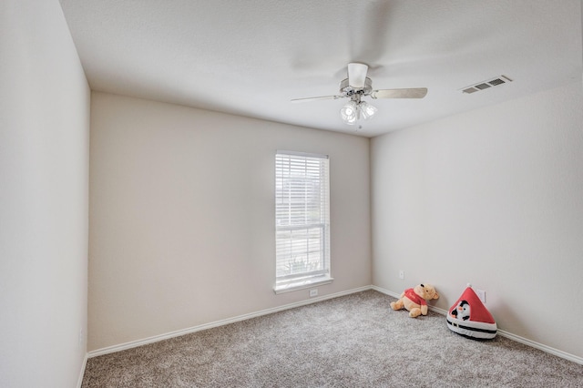 spare room featuring carpet floors, ceiling fan, visible vents, and baseboards