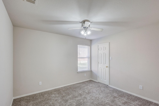 carpeted spare room featuring visible vents, a ceiling fan, and baseboards