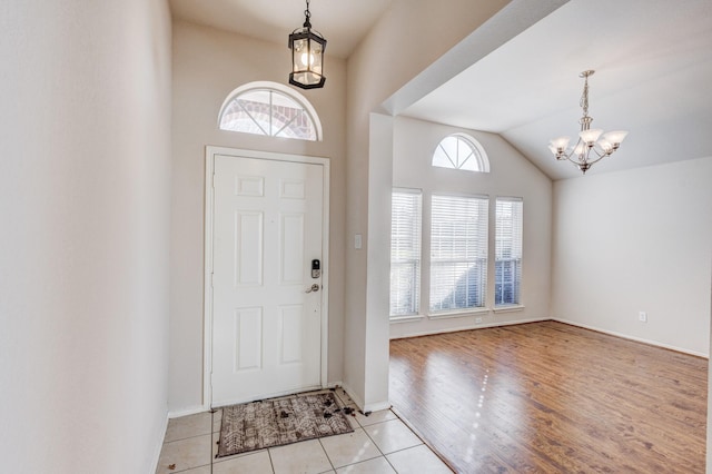 entryway featuring light tile patterned floors, vaulted ceiling, baseboards, and an inviting chandelier