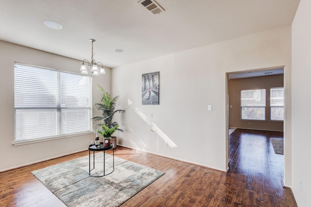 interior space featuring a chandelier, visible vents, baseboards, and wood finished floors