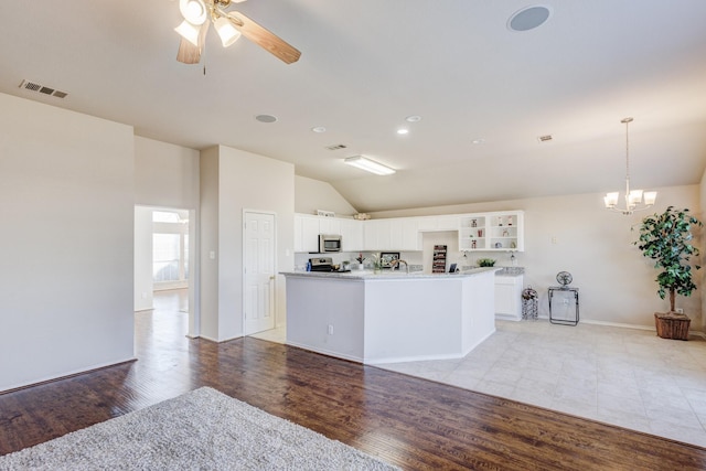 kitchen with light wood-style floors, vaulted ceiling, visible vents, and stainless steel appliances