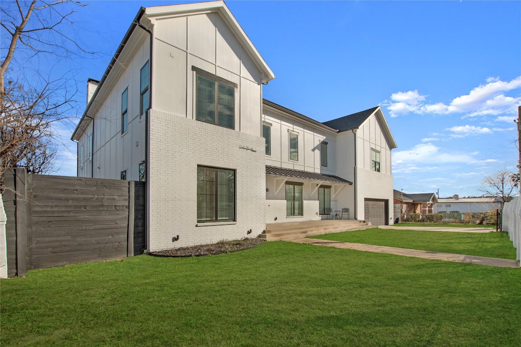 rear view of house with a garage, concrete driveway, a lawn, fence, and brick siding