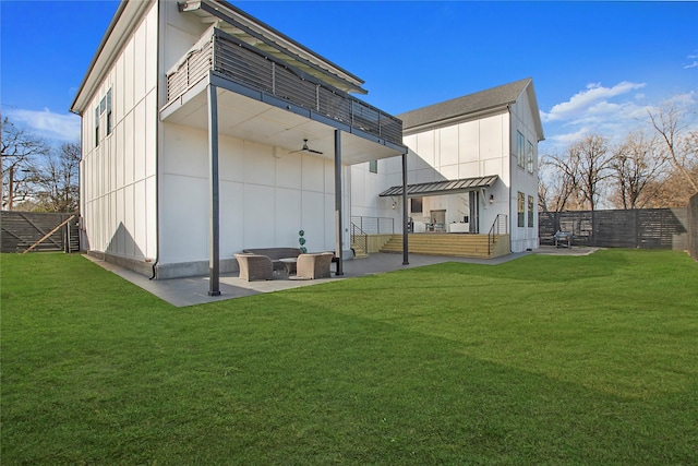 rear view of property featuring board and batten siding, a patio area, a lawn, and a fenced backyard