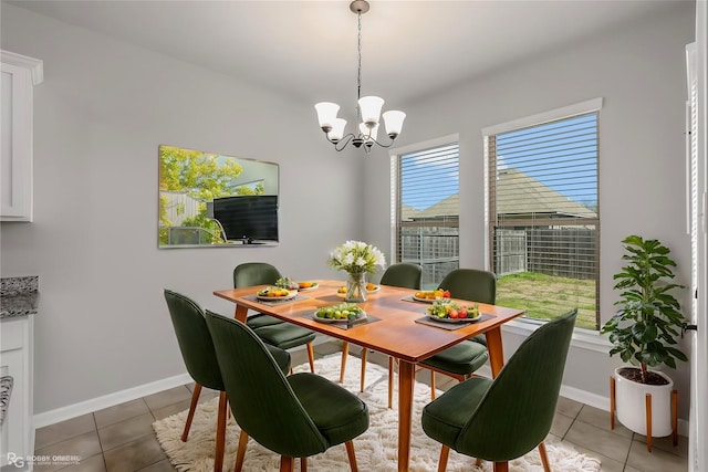 dining area featuring an inviting chandelier, baseboards, and tile patterned floors