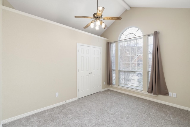 spare room with vaulted ceiling with beams, light carpet, baseboards, and a ceiling fan