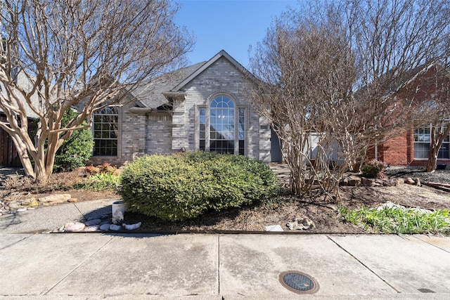 view of front of home featuring brick siding and roof with shingles