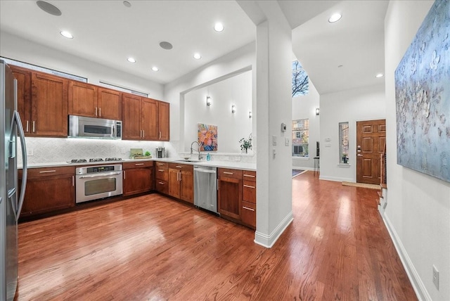 709 E 1st St, Fort Worth, TX 76102 - kitchen featuring appliances with stainless steel finishes, wood finished floors, light countertops, backsplash, and a sink