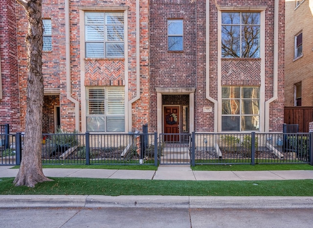 multi unit property featuring a fenced front yard and brick siding