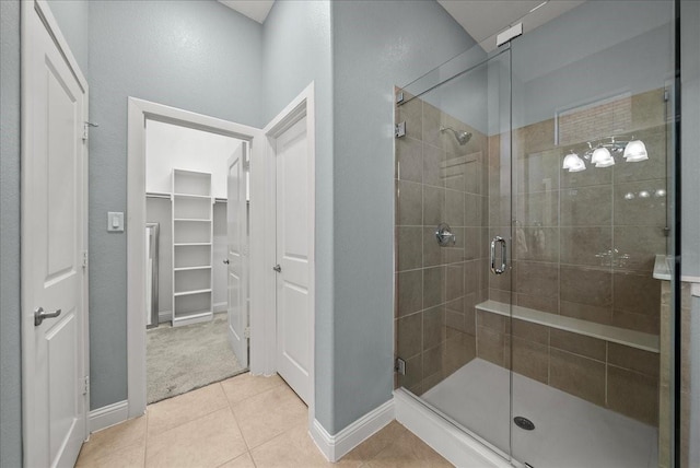 709 E 1st St, Fort Worth, TX 76102 - full bathroom with a stall shower, a spacious closet, baseboards, and tile patterned floors