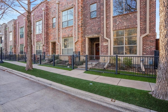 view of front of home featuring brick siding and fence