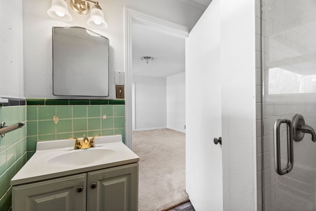 bathroom with a shower with door, tile walls, and vanity