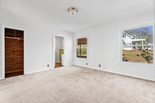 unfurnished bedroom featuring carpet floors, multiple windows, connected bathroom, and baseboards