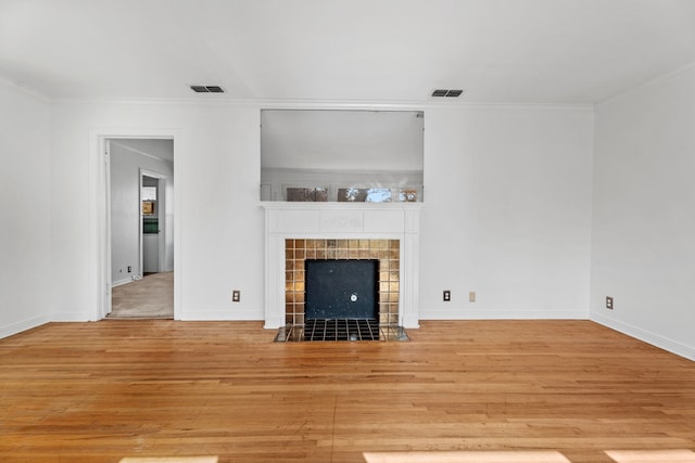 unfurnished living room featuring light wood-style floors, visible vents, and a tiled fireplace