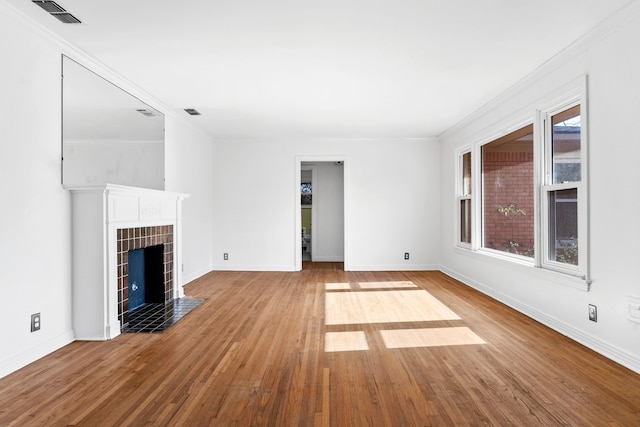 unfurnished living room featuring baseboards, visible vents, a fireplace with flush hearth, wood finished floors, and crown molding