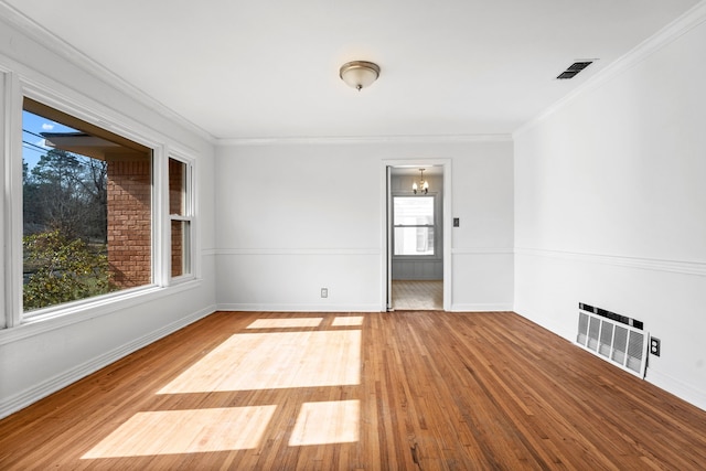 empty room featuring ornamental molding, wood finished floors, and baseboards