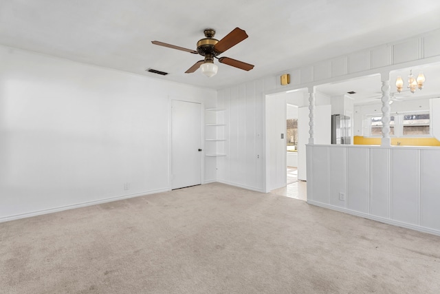 spare room with light carpet, visible vents, and ceiling fan with notable chandelier