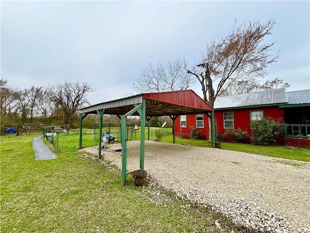 view of home's community with a carport, a lawn, and gravel driveway