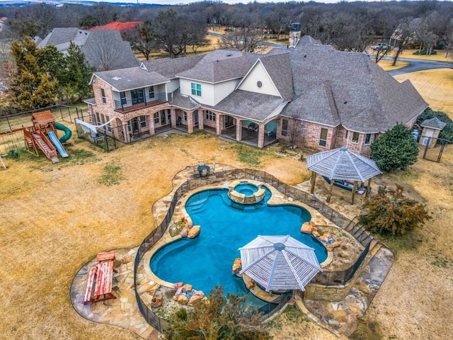 view of pool with a pool with connected hot tub, a playground, fence, and a gazebo