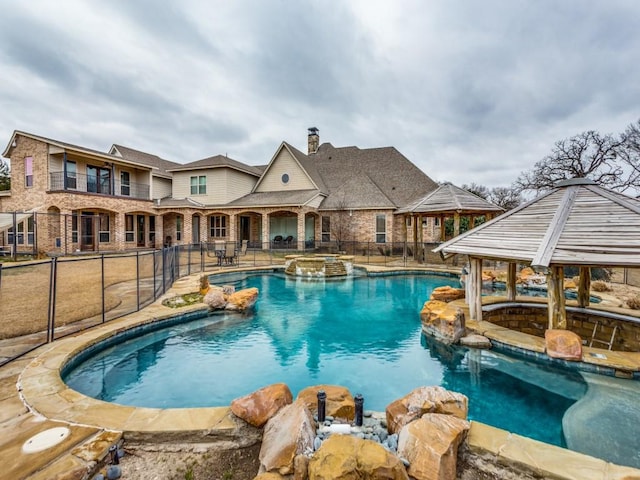 view of pool with a pool with connected hot tub, fence, and a gazebo