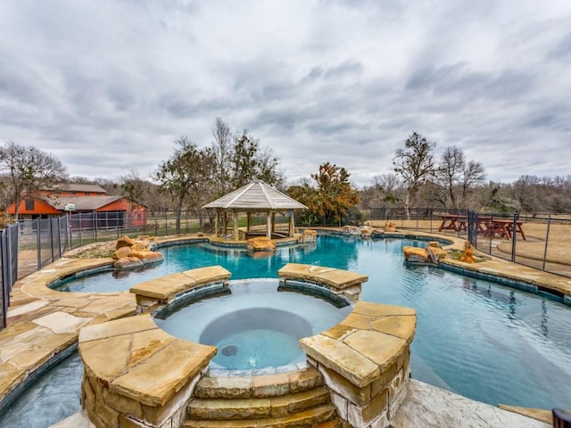 view of pool with a gazebo, fence, and a pool with connected hot tub