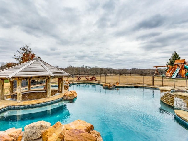 view of swimming pool featuring a fenced in pool, playground community, fence, and a gazebo