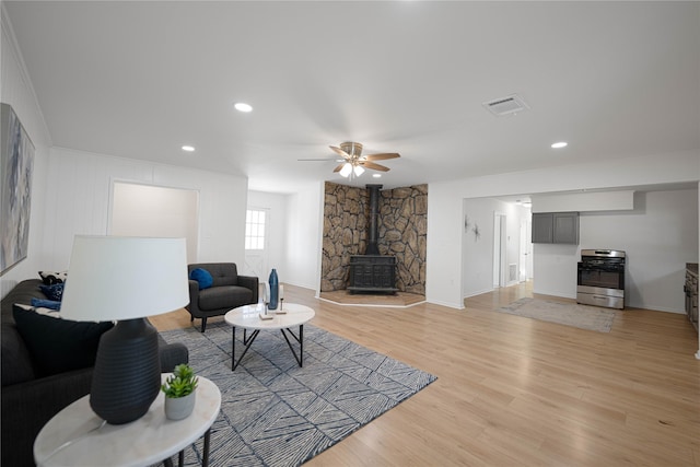 living room featuring recessed lighting, visible vents, light wood-style flooring, a wood stove, and ceiling fan