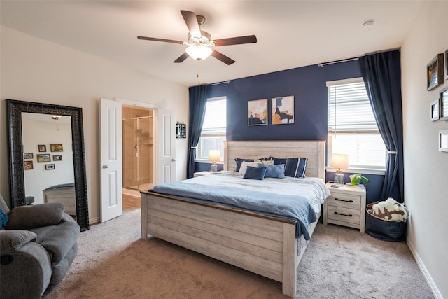 bedroom featuring a ceiling fan, light colored carpet, baseboards, and ensuite bathroom