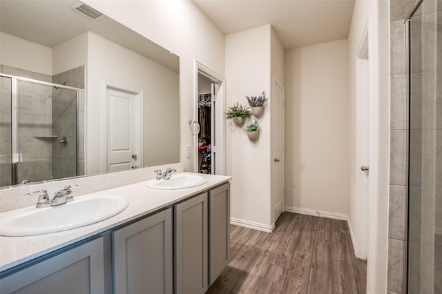 bathroom with a spacious closet, visible vents, a sink, and wood finished floors