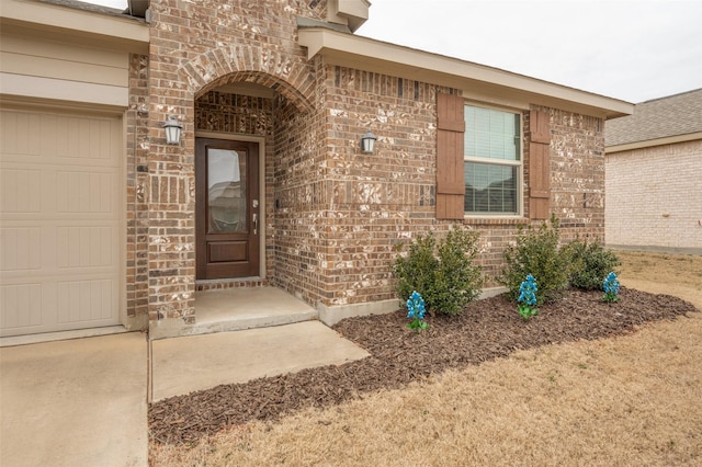 entrance to property with a garage and brick siding