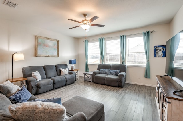 living area with light wood finished floors, baseboards, visible vents, and ceiling fan