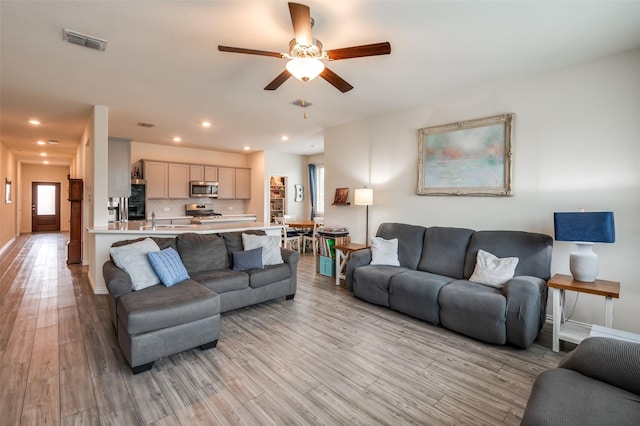 living area featuring ceiling fan, light wood-type flooring, visible vents, and recessed lighting