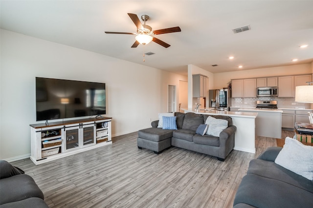 living room with light wood-style floors, baseboards, and visible vents