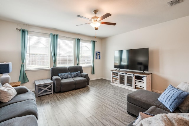 living room featuring a ceiling fan, wood finished floors, visible vents, and baseboards