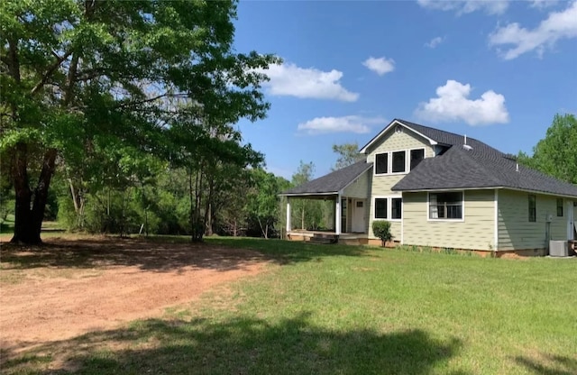 back of property with a yard, a shingled roof, and central AC