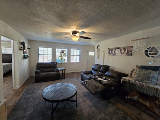 living area featuring dark wood-style floors, a textured ceiling, and a ceiling fan