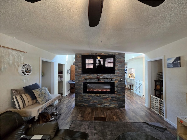 living room featuring dark wood-style flooring, a fireplace, and a textured ceiling