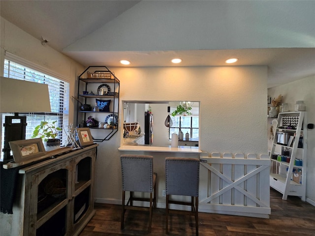 kitchen with a kitchen breakfast bar, vaulted ceiling, dark wood-style flooring, and light countertops