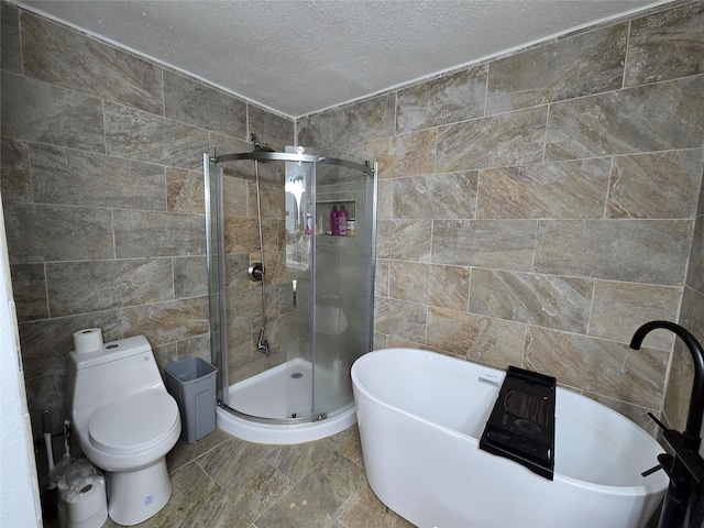 full bathroom featuring a shower stall, tile walls, toilet, and a textured ceiling