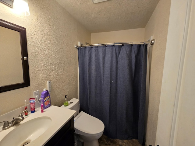 full bath with a textured wall, toilet, curtained shower, a textured ceiling, and vanity