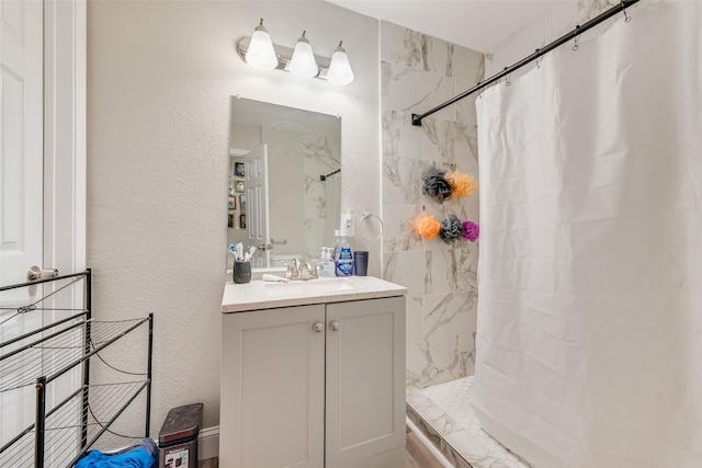 full bath featuring tiled shower / bath combo, a textured wall, and vanity