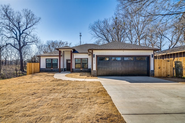 view of front of house with a garage, concrete driveway, stone siding, fence, and board and batten siding