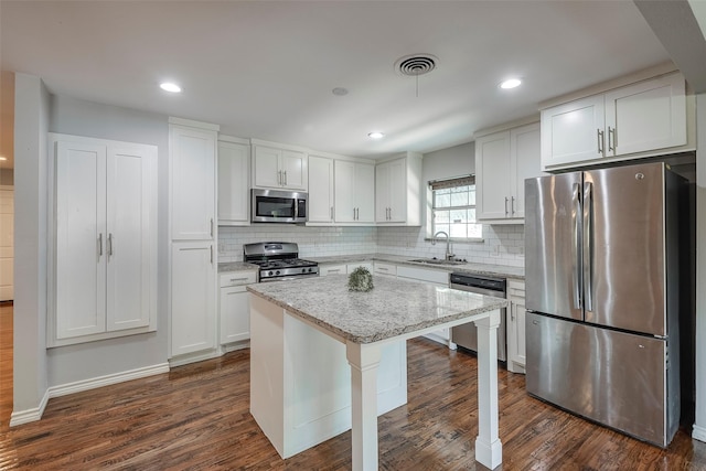 kitchen featuring a breakfast bar, a kitchen island, visible vents, white cabinets, and appliances with stainless steel finishes