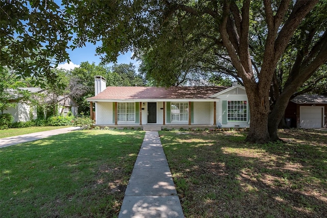 ranch-style house featuring a front yard, covered porch, brick siding, and a chimney