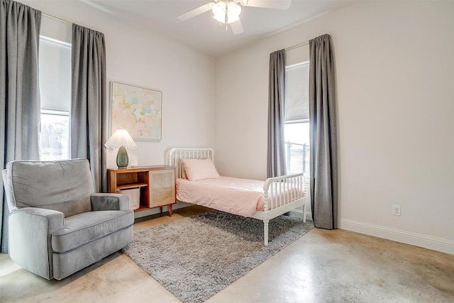 bedroom featuring multiple windows, concrete floors, a ceiling fan, and baseboards