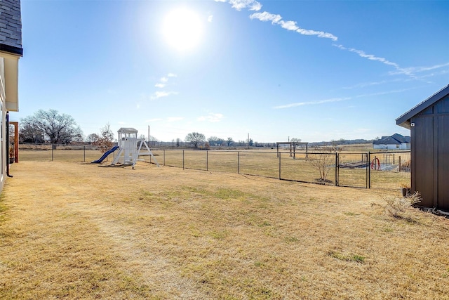 view of yard featuring a rural view, a playground, and fence