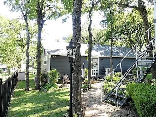 view of front of property featuring stairway, a front yard, and fence