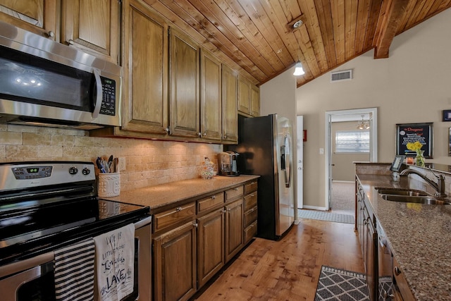 kitchen with lofted ceiling with beams, stone countertops, a sink, visible vents, and appliances with stainless steel finishes